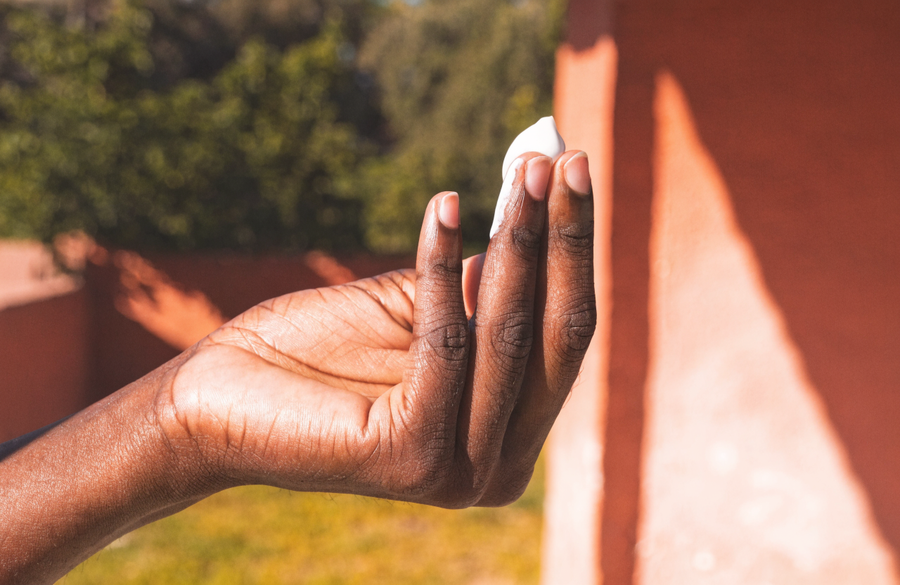 A two-finger length of sunscreen held up in hard South African sunlight.