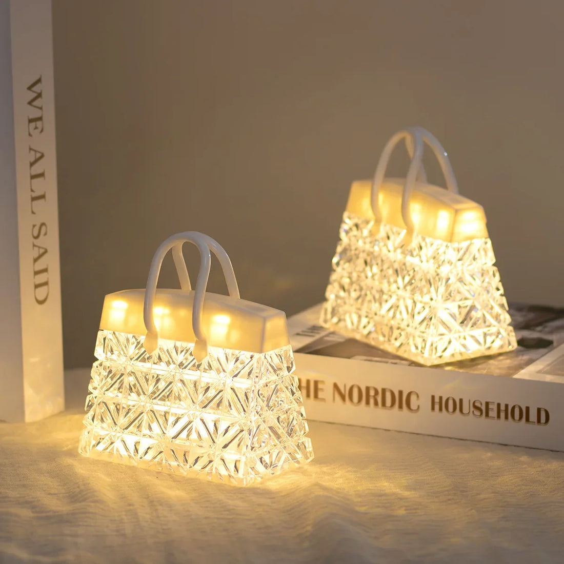 Two crystal handbag lamps glowing on a shelf beside books