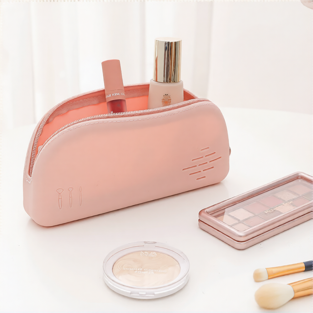 Pink silicone makeup pouch holding a foundation bottle and brushes