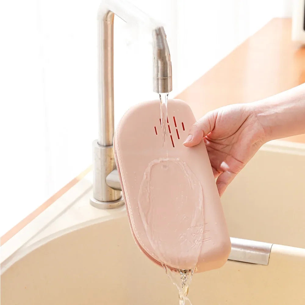 The pink silicone pouch being rinsed under a tap