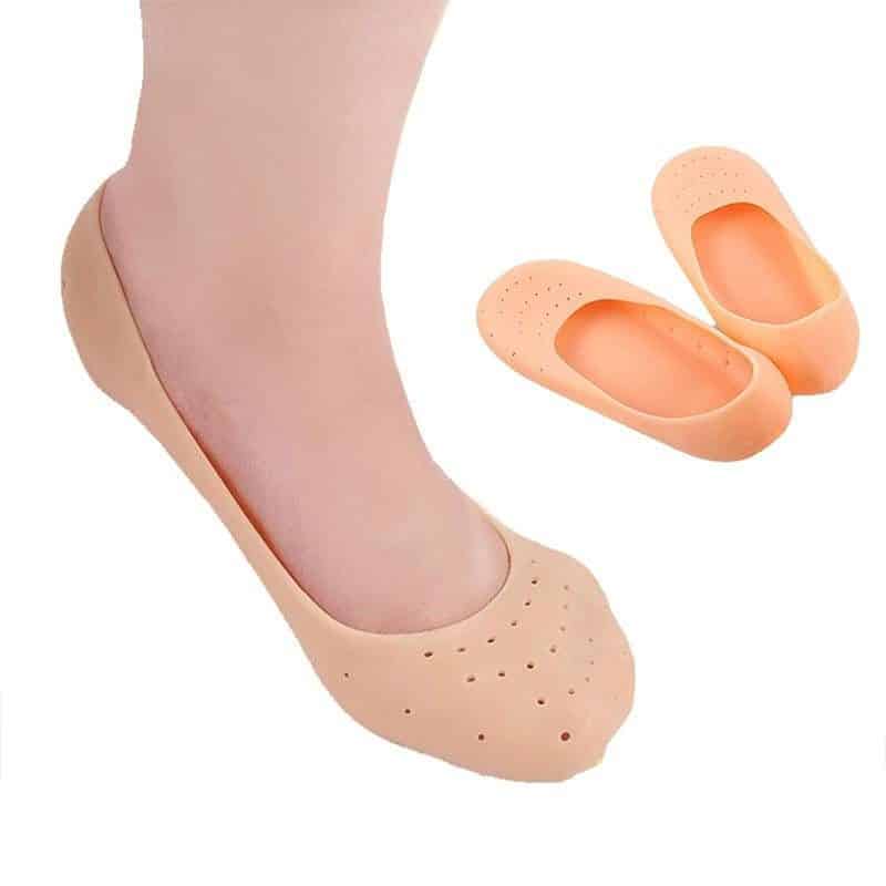 A foot wearing a silicone moisturising sock, with a spare pair beside it