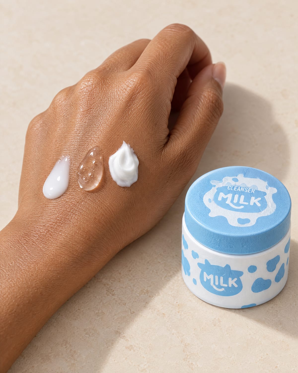 Three dabs of product on the back of a hand, beside an open jar